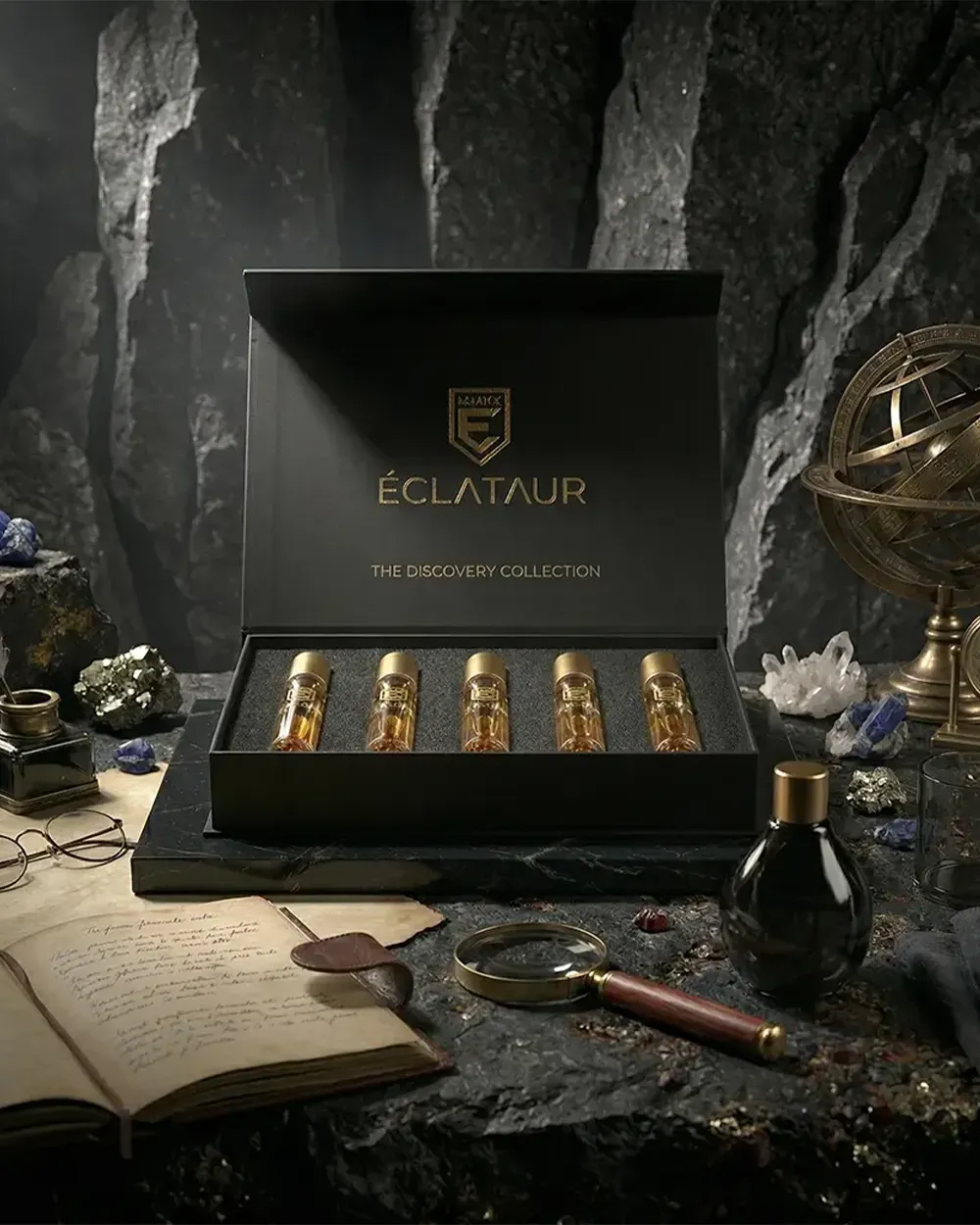 The Discovery Gift Set open among dark minerals and brass instruments, five gold-capped sprays in the EVA insert